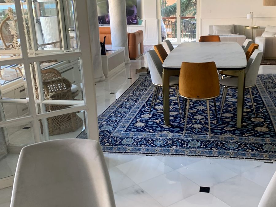 Sala da pranzo con tavolo bianco e sedie arancioni su un tappeto blu, in un'abitazione di pregio dopo il trasloco